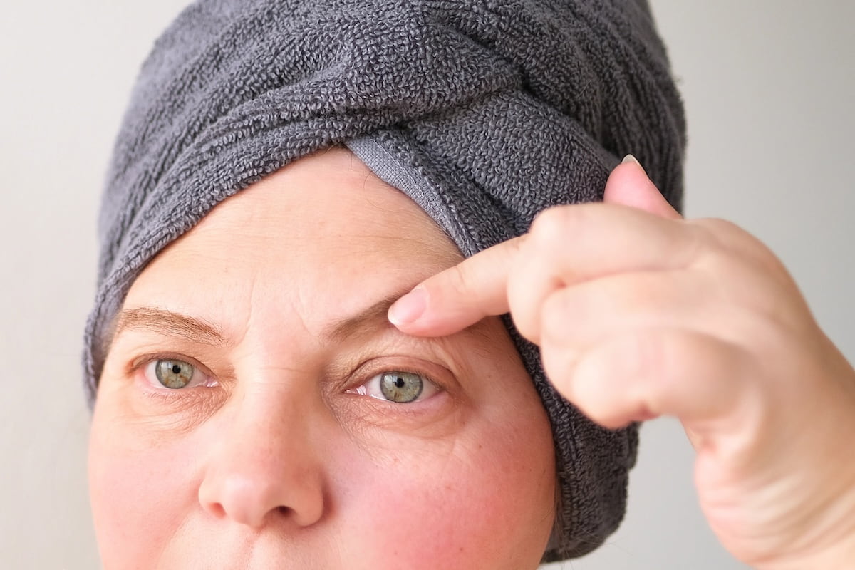 Mujer viendo sus párpados, buscando los tratamientos correctos para arreglar el párpado caído y recuperar la firmeza visual.